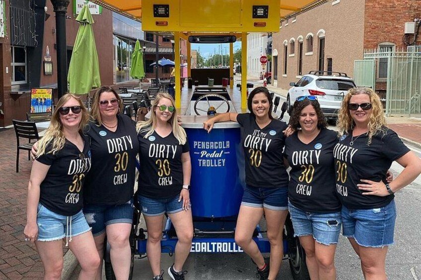 A group of people wearing matching 'Dirty 30 Crew' t-shirts standing next to a trolley. 3