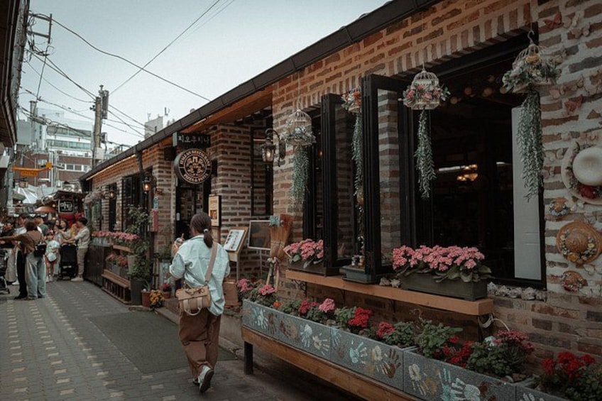 Una calle con edificios de ladrillo, macetas con flores y adornos colgantes. 5