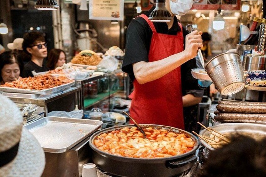 Un vendedor de comida callejera preparando alimentos en un puesto con varios utensilios de cocina e ingredientes a la vista. 4