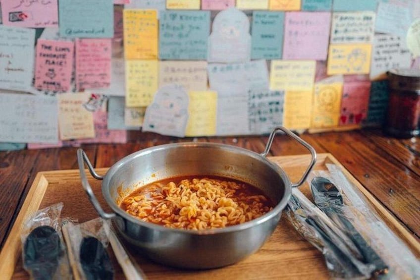 Un tazón de fideos ramen sobre una bandeja de madera, con notas adhesivas al fondo. 2