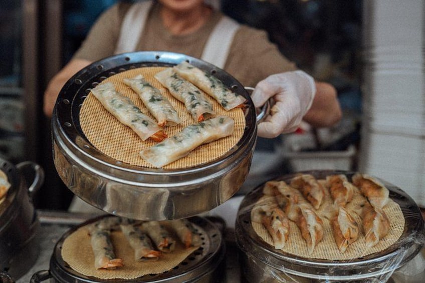 Una persona cocinando rollitos primavera en una estufa. 3
