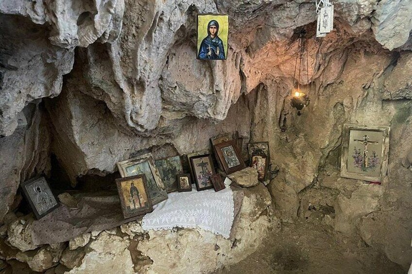 A cave interior with religious icons and a lit candle. 3