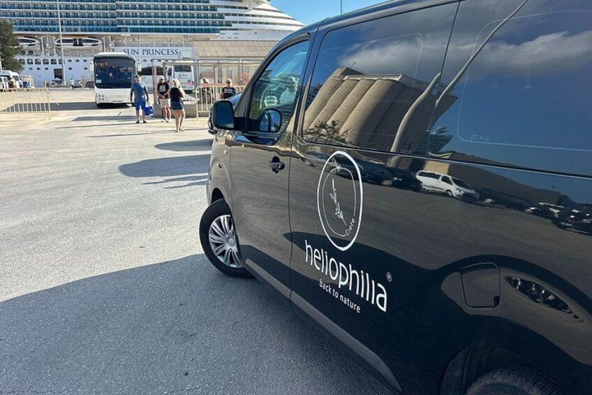 A heliophilia van parked near a cruise ship terminal with a large building in the background. 2