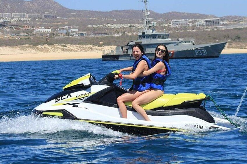 Due persone sullo sci nautico, acqua, una barca e una spiaggia sullo sfondo. 4