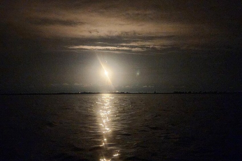 Een nachtelijk zeeschap met een heldere lichtbron die op het wateroppervlak reflecteert. 2