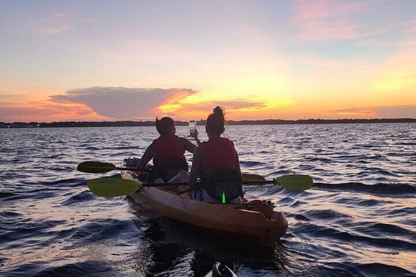 A couple of girls enjoy a magnificent sunset while kayaking.