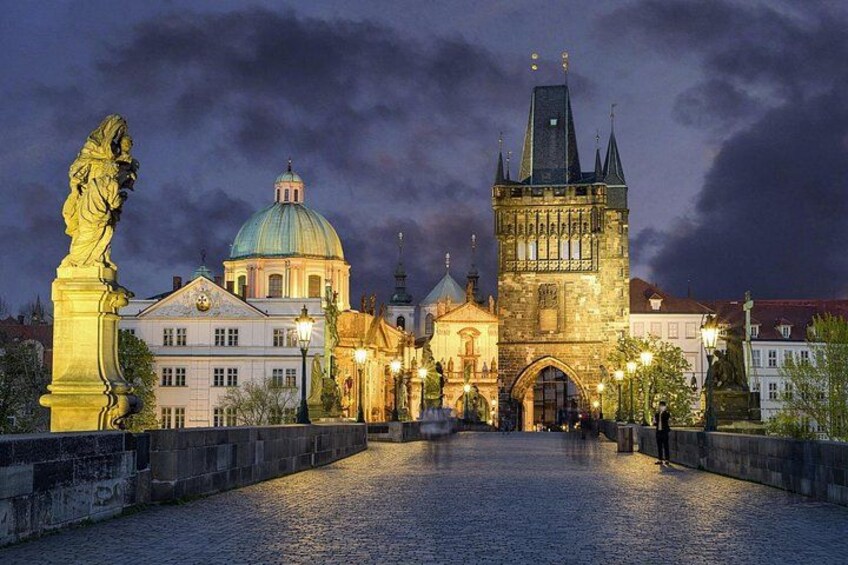 A historic bridge with a tower, a statue, and a building with a dome. 4