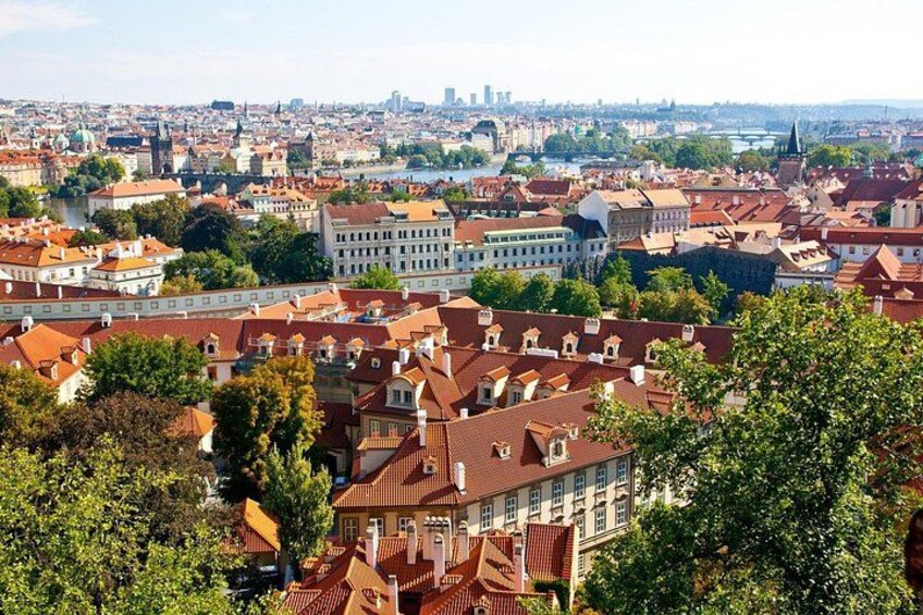 A cityscape with red-roofed buildings, a river, and a distant view of a city skyline. 3