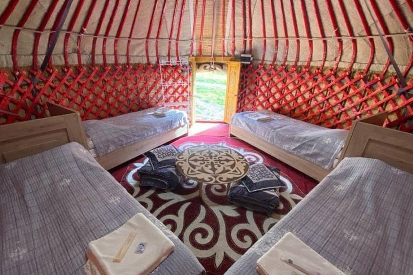 A traditional yurt with four beds arranged around a central patterned rug. 4