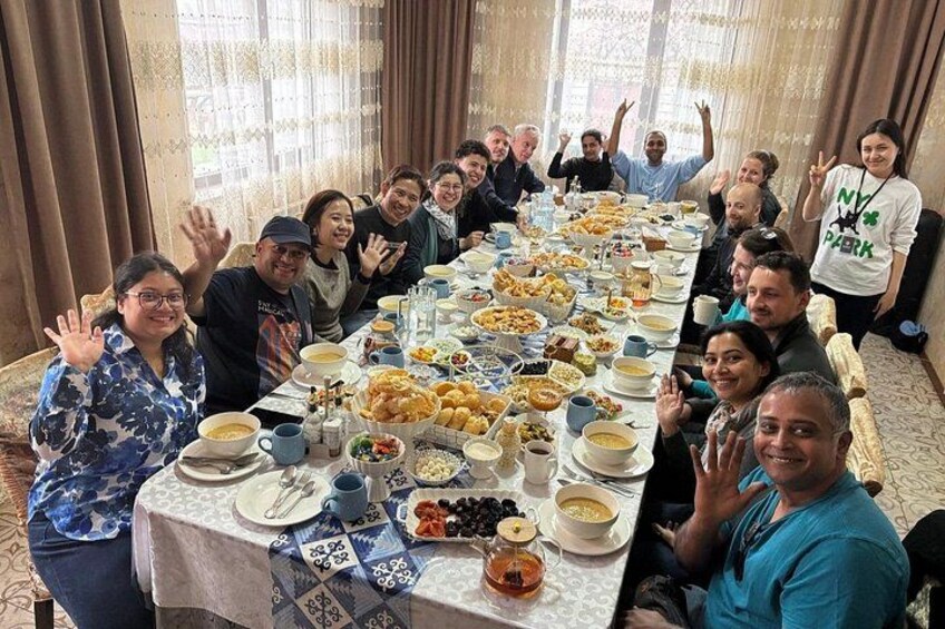 A group of people seated around a long table with various dishes and drinks. 2
