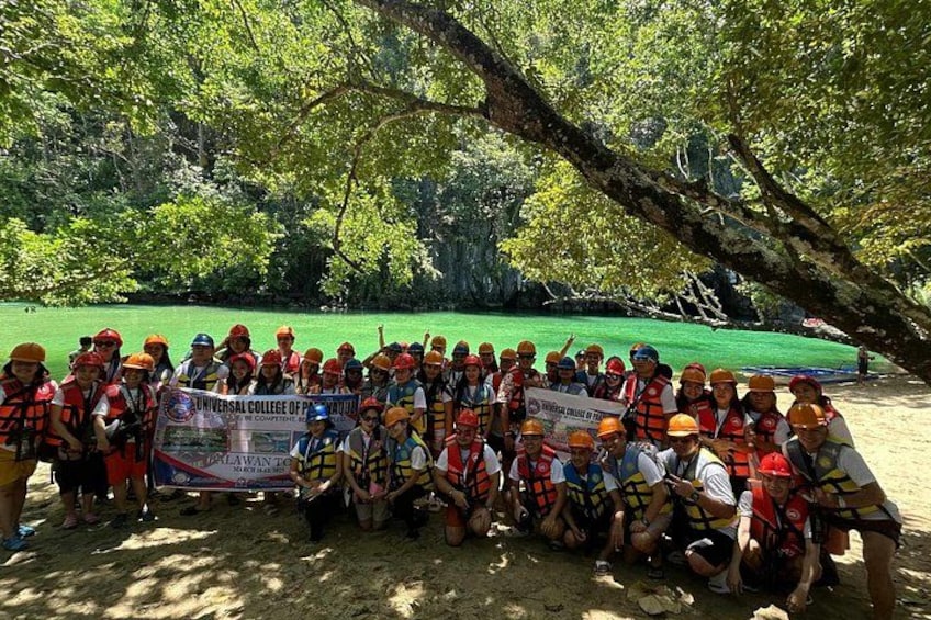 A group of people in a forested area holding a banner. 4