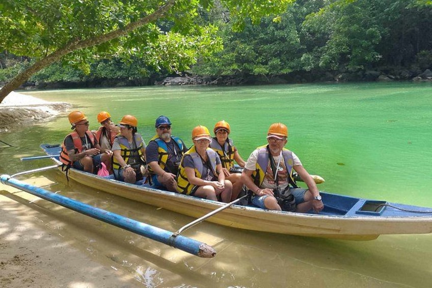 A group of people in a canoe on a calm river, surrounded by greenery. 2