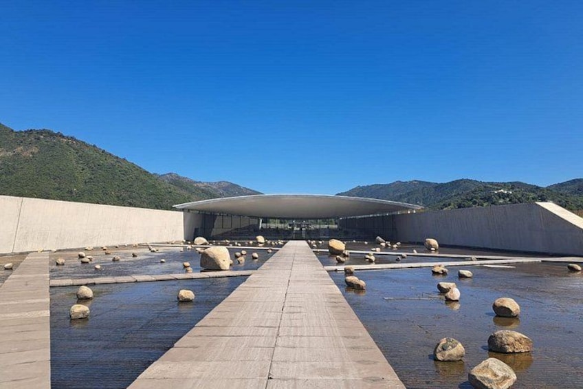 A modern building with a unique roof design, surrounded by a water feature with rocks. 5