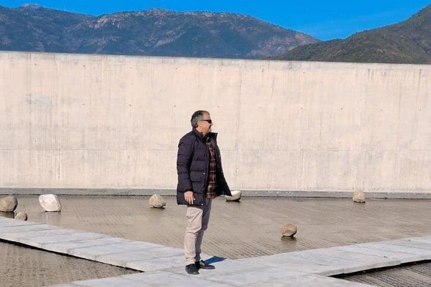 A person standing on a concrete platform with mountains in the background. 2