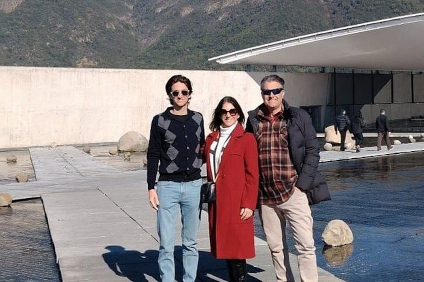 Three people standing in front of a modern building with a reflective pool. 3