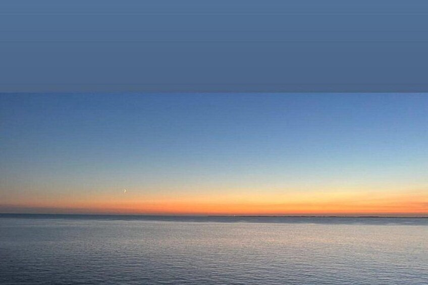 Een rustige zee bij zonsondergang met een heldere lucht. 3