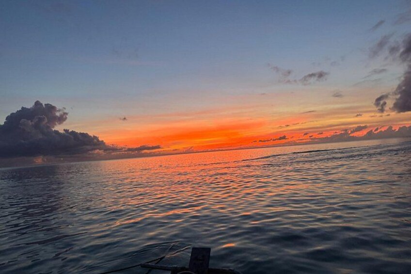 Een zonsondergang boven een rustige zee, met een houten steiger op de voorgrond. 2