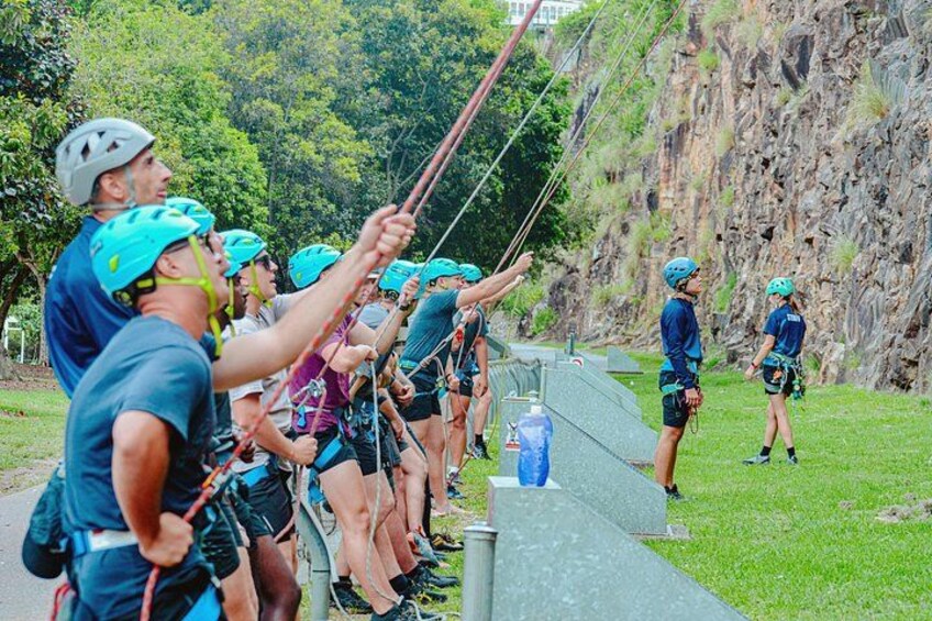 Een groep mensen met helmen en tuigjes bereidt zich voor op een zipline-activiteit. 3