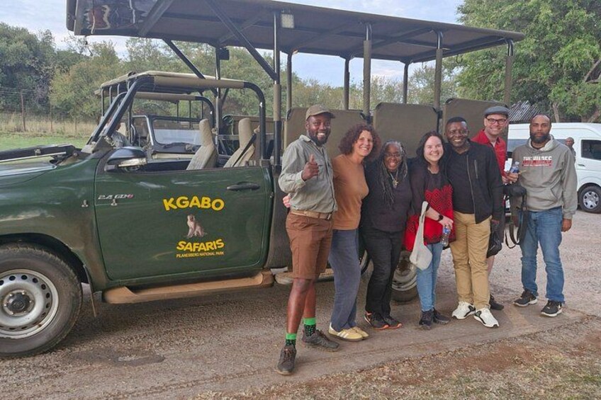 A group of people posing in front of a safari vehicle with 'KGABO SAFARIS' written on it. 5
