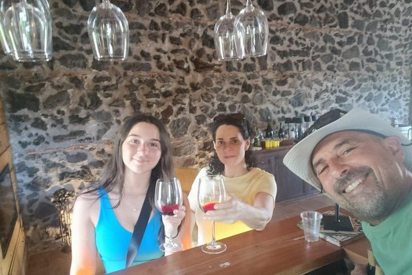 Three people at a bar with stone walls and hanging lights. 4