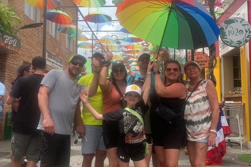 A group of people standing under colorful umbrellas on a street. 4