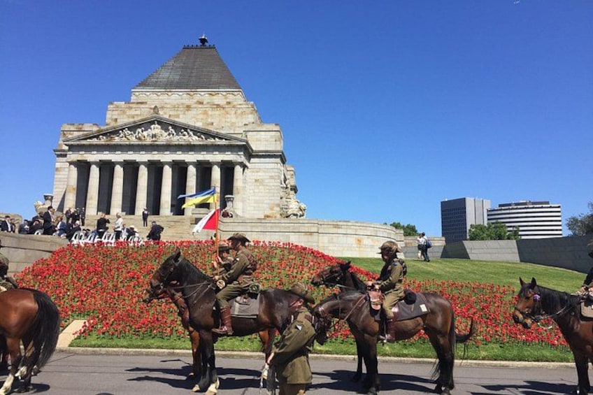 A monument with columns, a flag, and people in uniform on horseback. 4