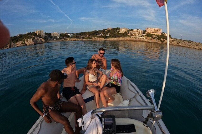 A group of people on a boat with a rocky shoreline and buildings in the background. 2