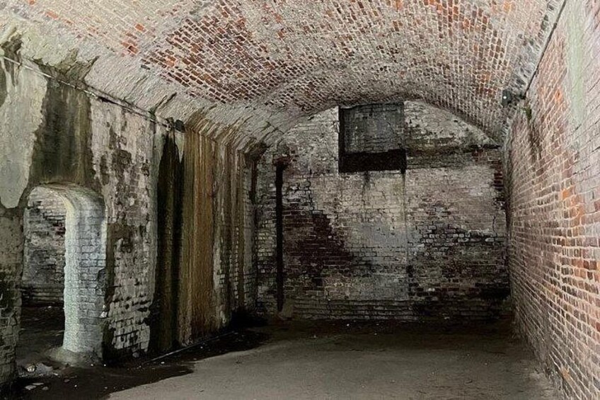 An abandoned brick tunnel with a concrete floor and a small window. 2