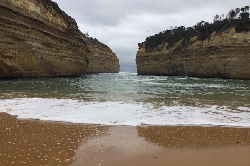 A beach with a rocky cliff and ocean waves. 2
