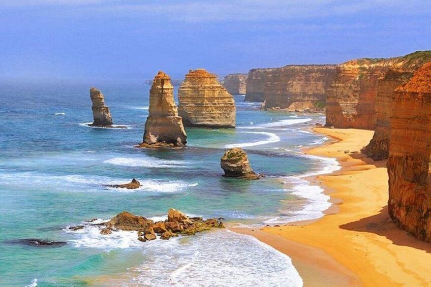 A coastal landscape with prominent rock formations and a sandy beach. 1