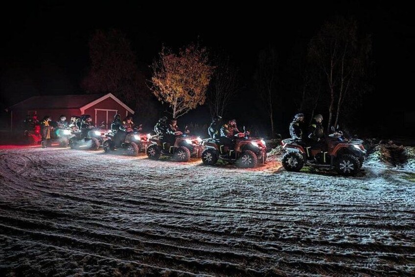 En grupp människor på terrängfordon som kör på en snötäckt stig i mörkret. 2