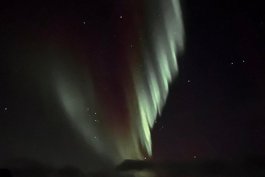 Norrskenet (Aurora Borealis) mot en mörk himmel och svagt synliga stjärnor. 4