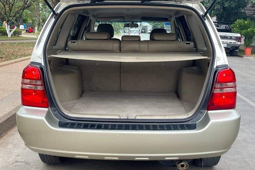 The rear of a beige station wagon with an open trunk, beige interior, and visible rear lights. 2