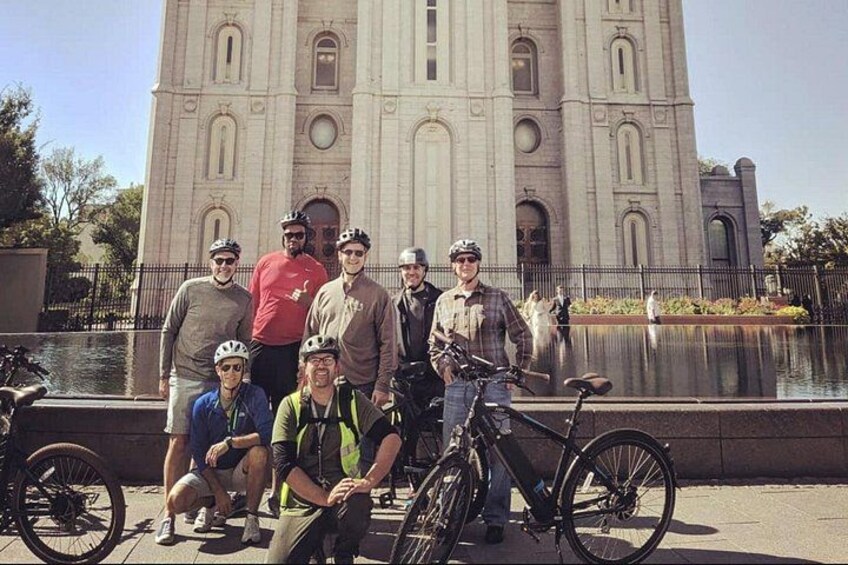 A group of people with bicycles in front of a large building. 2