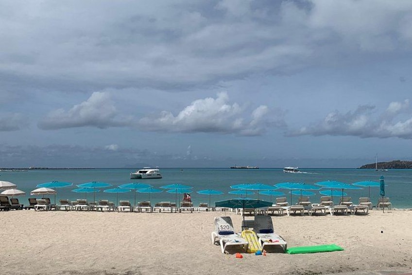 A beach with rows of sun loungers and umbrellas, a green mat, and a lifeguard stand. 3
