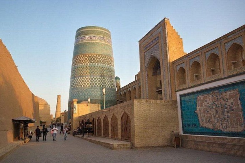 A historic building with a tall tower, a large mural, and a paved walkway. 3