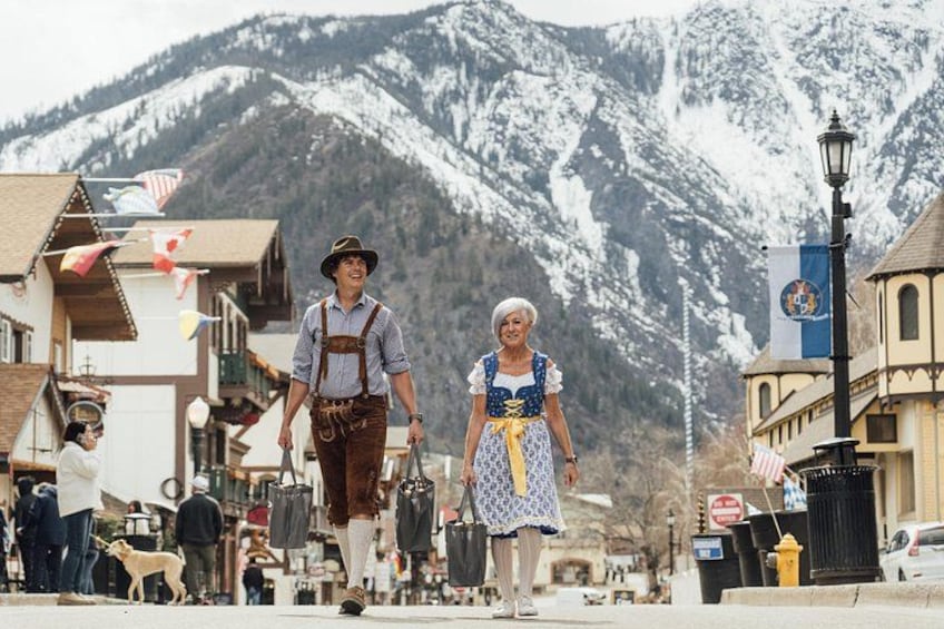 Ein verschneiter Berg im Hintergrund, ein traditionelles Gebäude und eine belebte Straße mit Menschen. 2