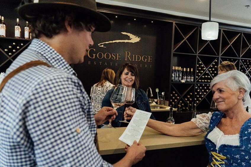 A wine tasting event at Goose Ridge Estate Winery with guests holding wine glasses and menus. 1