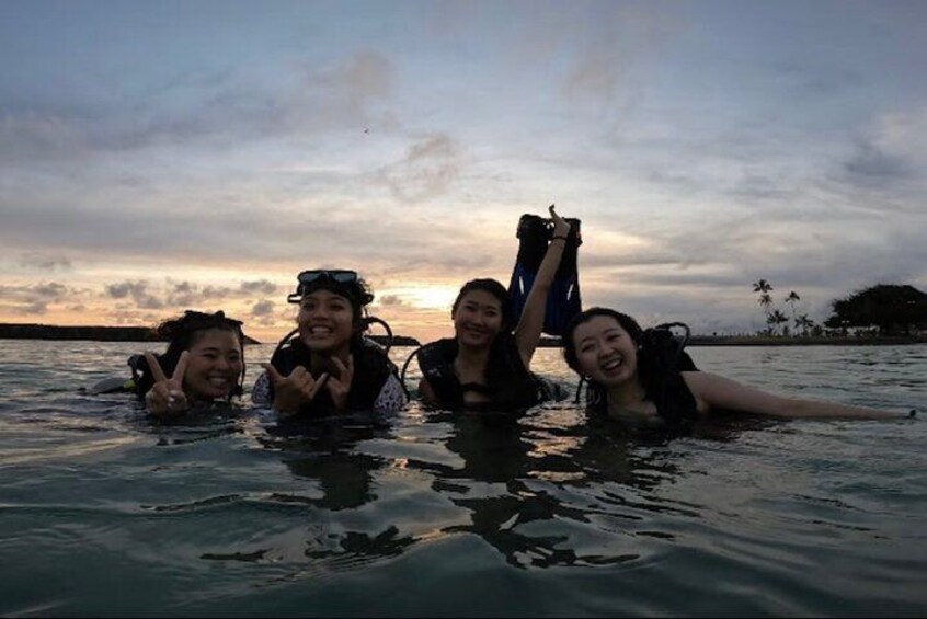 Four people in a body of water with a sunset in the background. 2