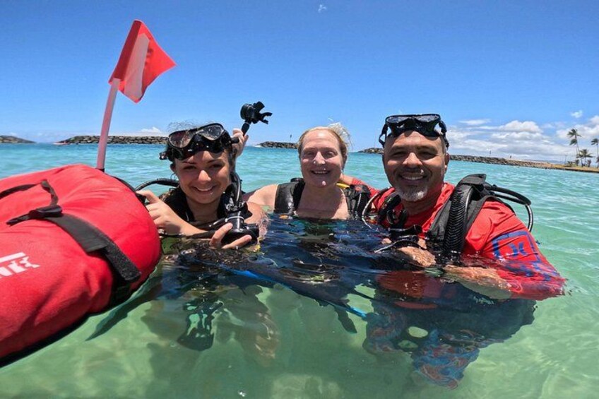 Three people snorkeling in clear water with a red flag in the background. 3