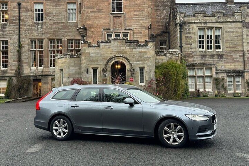A silver car parked in front of a historic building with large windows and a stone facade. 3