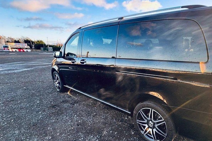 En svart skåpbil står parkerad på ett grusunderlag med en klar himmel i bakgrunden. 3