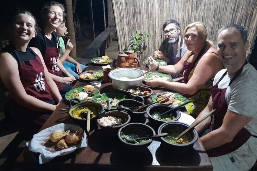 Un groupe de personnes est assis autour d’une table, devant différents plats et des récipients remplis de nourriture. 1