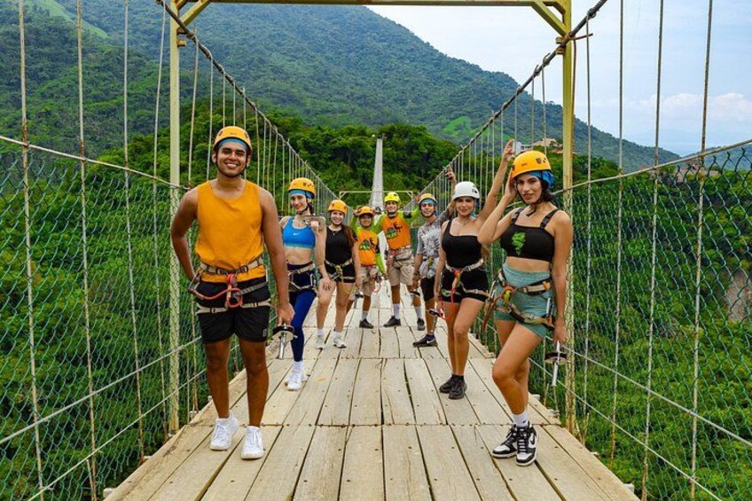 Een groep mensen op een hangbrug, met een bergachtig landschap op de achtergrond. 3