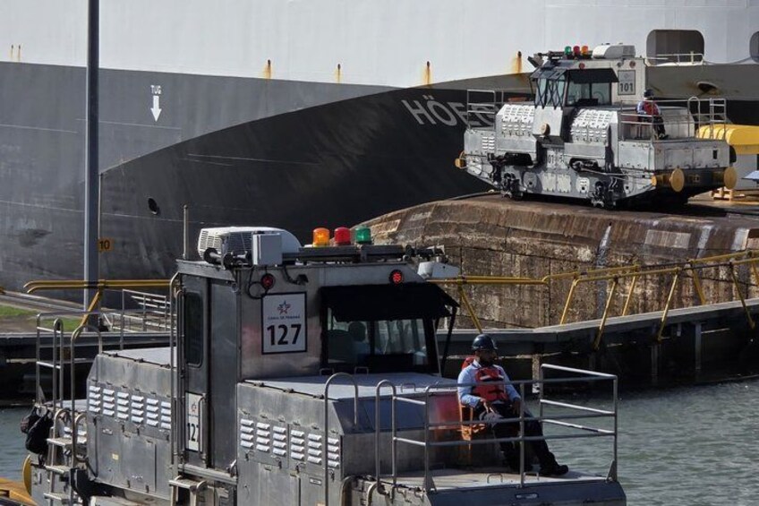 Ein großes Schiff liegt an einem Hafen aus, mit einem Kran und einer Person auf einer Plattform. 2
