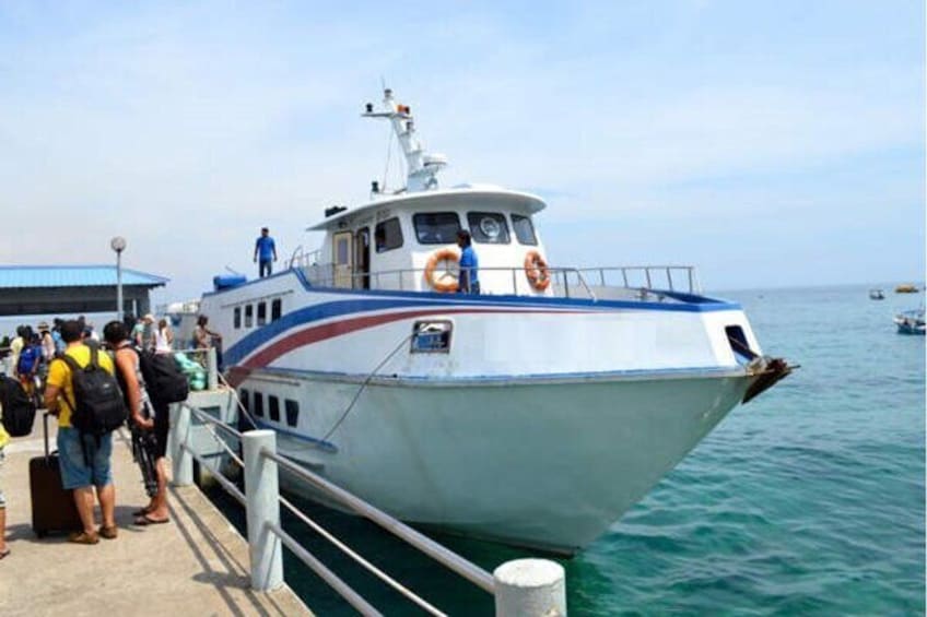 A boat docked at a pier with people boarding. 1