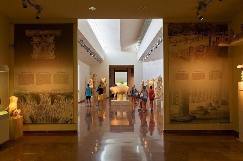 Un museo interno con pavimento lucido, sculture classiche e pannelli informativi. 1