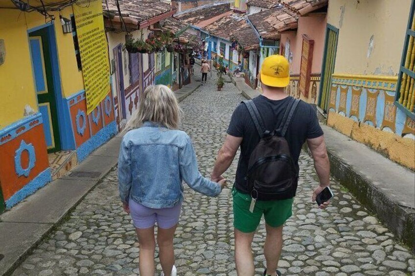 A couple walking down a cobblestone street in a colorful neighborhood. 1