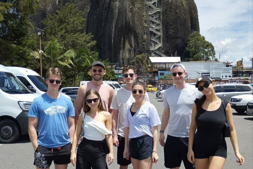A group of people standing in a parking lot with a large rock formation in the background. 4