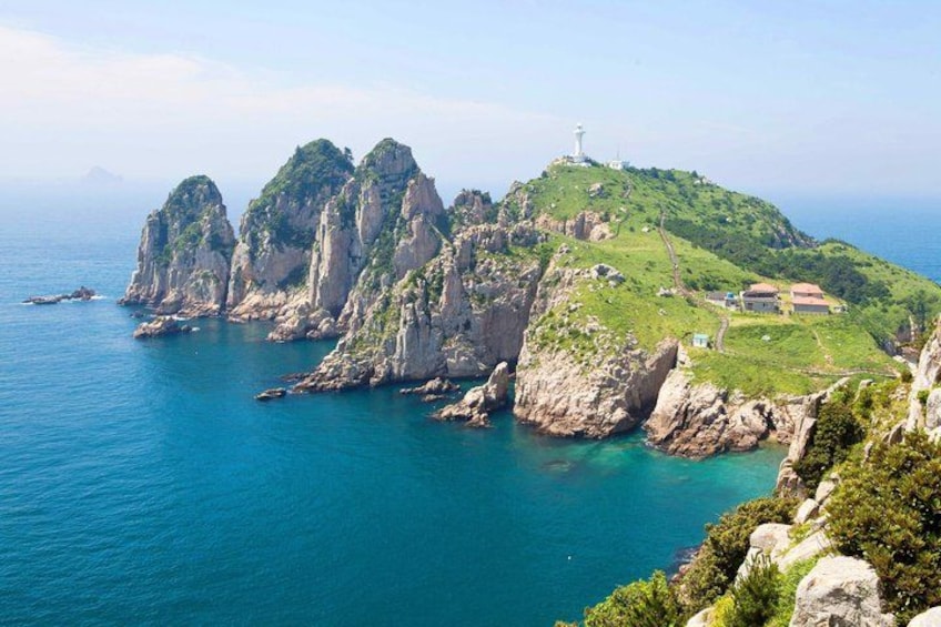 Un paisaje costero con acantilados rocosos, un faro y un pequeño asentamiento. 5